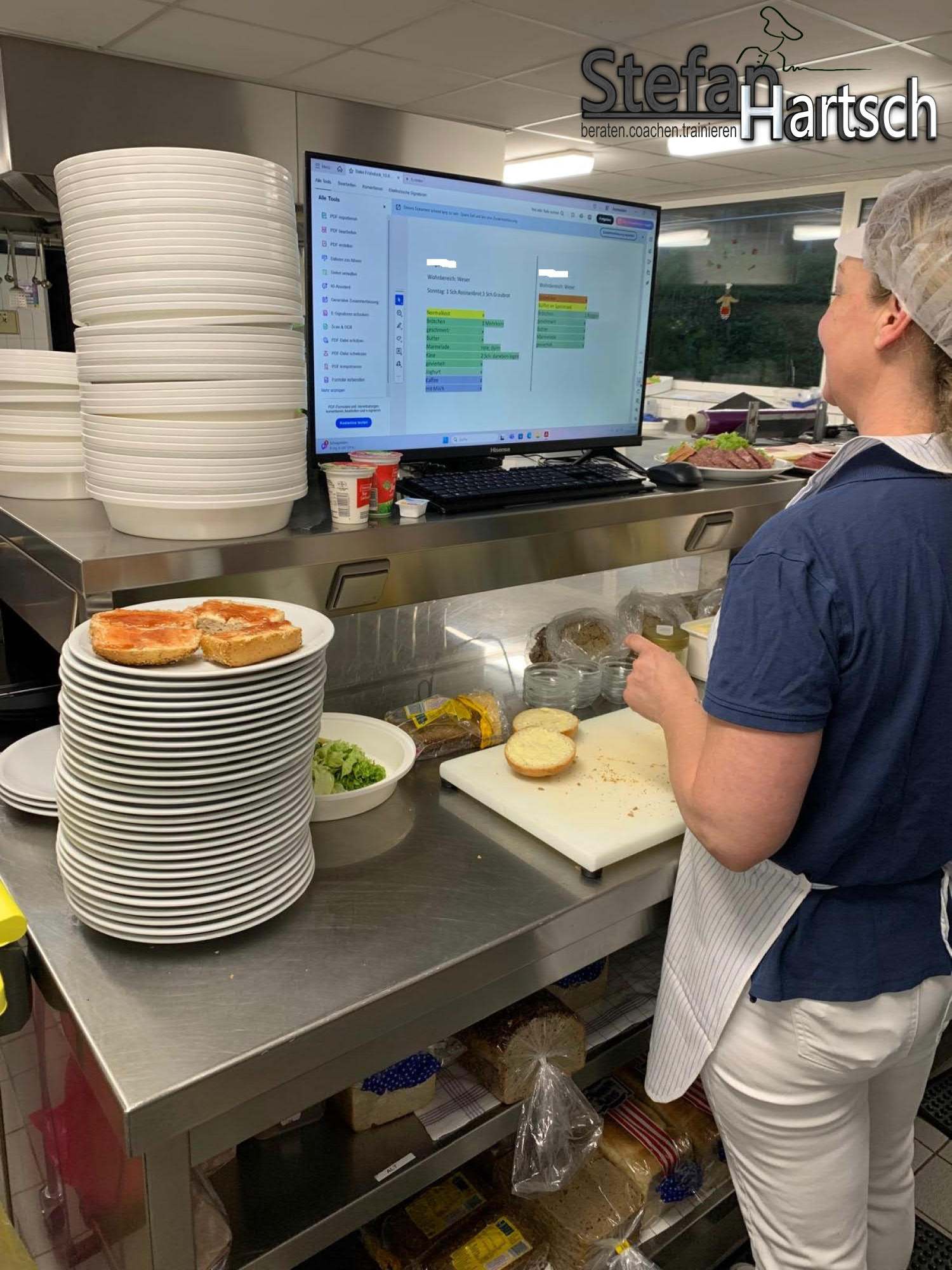 Zwei Mitarbeitende in einer Großküche arbeiten mit digitaler Bewohnerkarte am Bildschirm zur Menüplanung