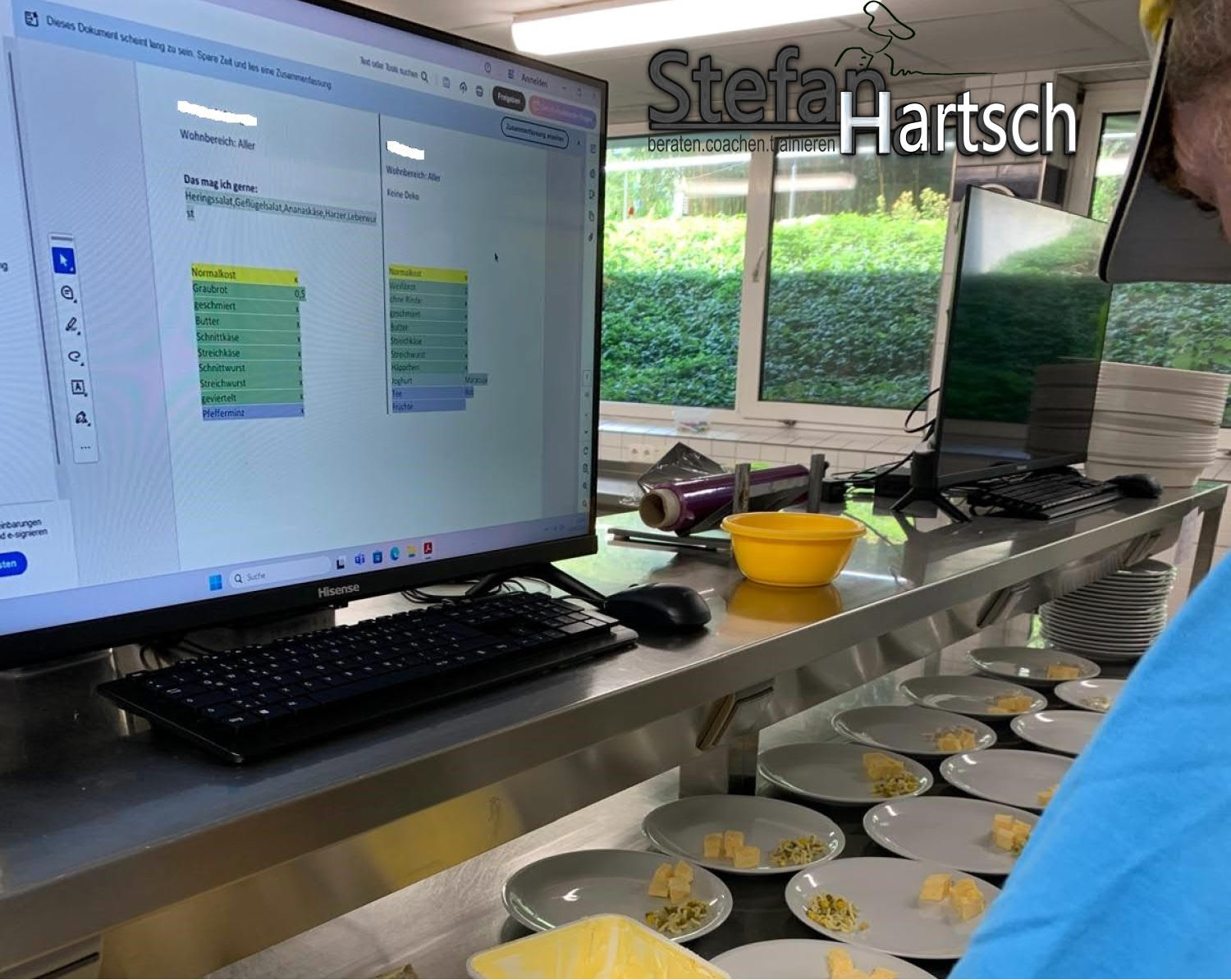 Zwei Mitarbeitende in einer Großküche arbeiten mit digitaler Bewohnerkarte am Bildschirm zur Menüplanung